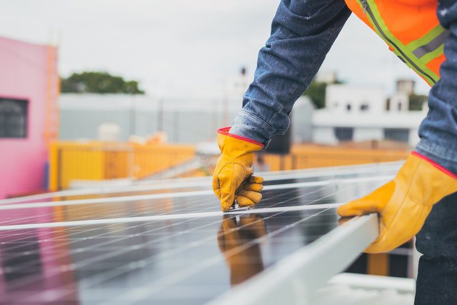 worker installing solar panel on top of building | Innovators Central