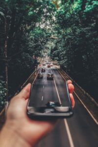 person holding smartphone merged with photo of cars on road