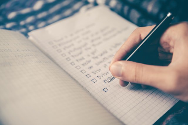 person writing a list of goals in notebook | Innovators Central