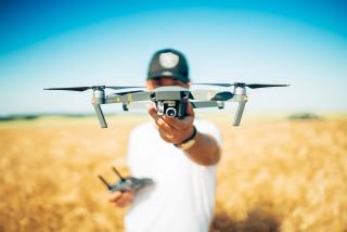man standing in field holding drone | Innovators Central